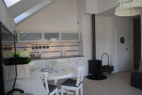 a kitchen with a white table and chairs in a room at Apartament Morski in Karwia
