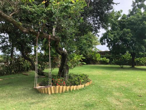 a swing hanging from a tree in a park at Casa paradise perto da praia Guarajuba - BA in Camacari