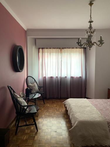 Un dormitorio con una cama y dos sillas y una ventana. en A Casa das Margaridas, en Oporto