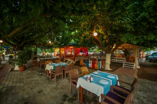 an outdoor restaurant with tables and chairs under a tree at Cirali Zakkum Bungalow in Cıralı
