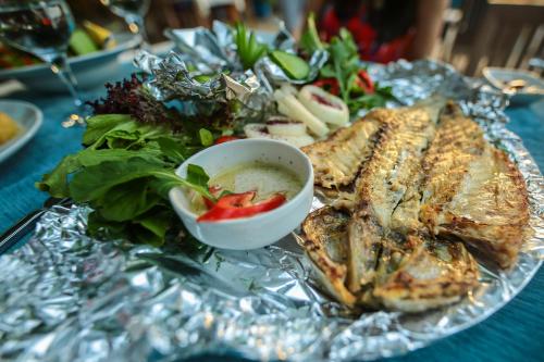 a plate of fish with a salad and a bowl of sauce at Cirali Zakkum Bungalow in Cıralı