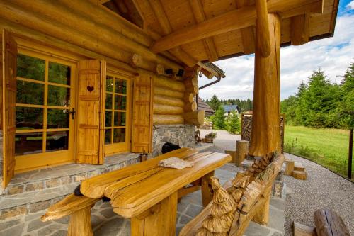 a porch of a log cabin with a wooden bench at KRALJICA ŠUME - Divjake Log Home in Hlevci