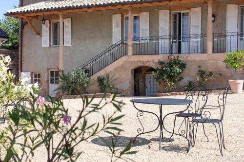 a table and chairs in front of a house at Chambres d'hôtes Vers la Croix in Leynes