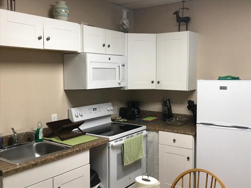 a kitchen with white cabinets and a sink and a refrigerator at Northern Peaks Motor Inn in Gorham
