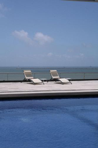 two chairs and a swimming pool next to the ocean at Mazagonia in Mazagón