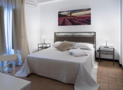 トレカスターニにあるDomus Giuliaeの白いベッド1台付きのベッドルーム1室(壁に絵画付)