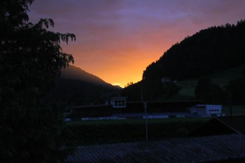 a sunset over a mountain with a house in the foreground at Ferienwohnung Brandstätter in Windischgarsten