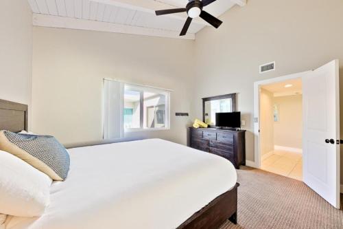 1 dormitorio con 1 cama blanca grande y ventilador de techo en Oceanfront Balboa Boardwalk Units I, II, & III, en Newport Beach