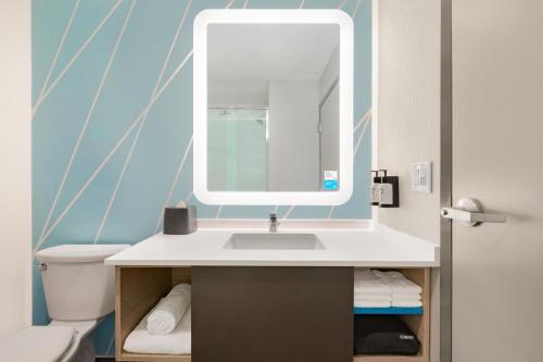 a bathroom with a sink and a mirror at Avid Hotel Cedar Rapids South - Arpt Area, an IHG Hotel in Cedar Rapids