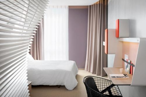 um quarto de hotel com uma cama branca e uma cadeira em Okko Hotels Nantes Château em Nantes