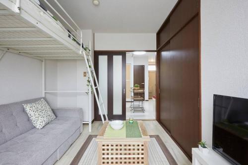 a living room with a couch and a tv at 松戸の快適ロフトベッド1DK 長期滞在にも Nomad松戸宿005 in Matsudo