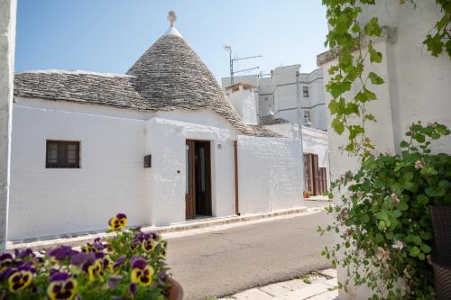 a white building with a pointed roof on a street at Trullo dal Cavaliere in Alberobello