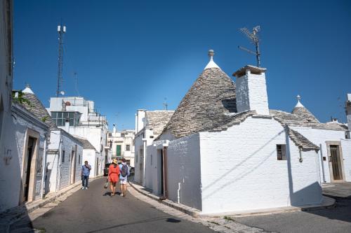 a group of people walking down a street with white buildings at Trullo dal Cavaliere in Alberobello