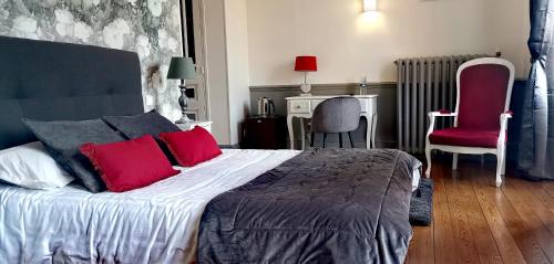 a bedroom with a large bed with red pillows at Logis Hotel La Tourelle du Beffroi in Bourbon-Lancy
