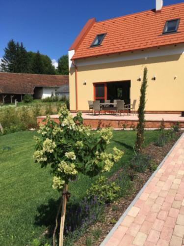 a garden in front of a house with a bush at Vendvidéki Pihenőházak in Felsőszölnök
