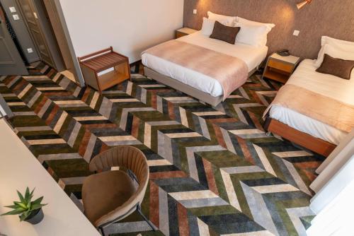 a hotel room with two beds and a table at D. Afonso Hotel & SPA in Monte Real