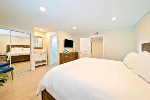 um quarto com uma grande cama branca e uma televisão em Newport Beach Condo Deluxe I & II em Newport Beach