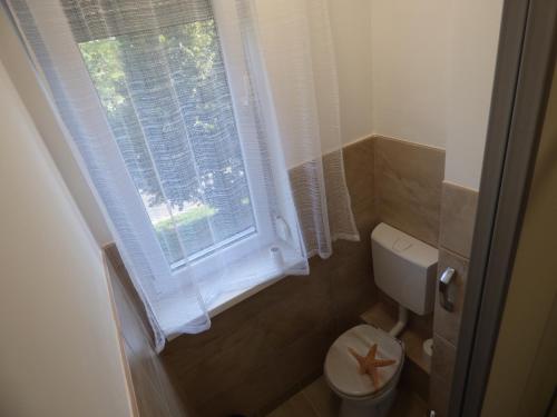 a small bathroom with a toilet and a window at Bega Apartman in Barcs