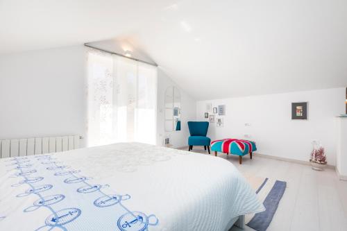 a white bedroom with a white bed and blue chairs at Apartments Priko 63 in Mali Lošinj
