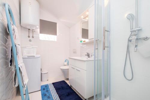 a white bathroom with a shower and a toilet at Apartments Priko 63 in Mali Lošinj