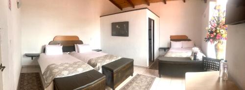 ein Schlafzimmer mit 2 Betten in einem Zimmer mit einem Tisch in der Unterkunft Regis Hotel Boutique in Mineral del Monte