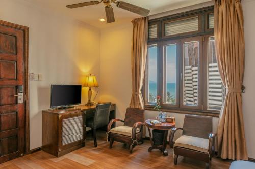 a living room with a television and a table and chairs at Chu Hotel in Danang