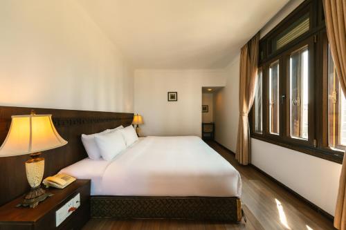 a bedroom with a bed and a lamp and a window at Chu Hotel in Da Nang