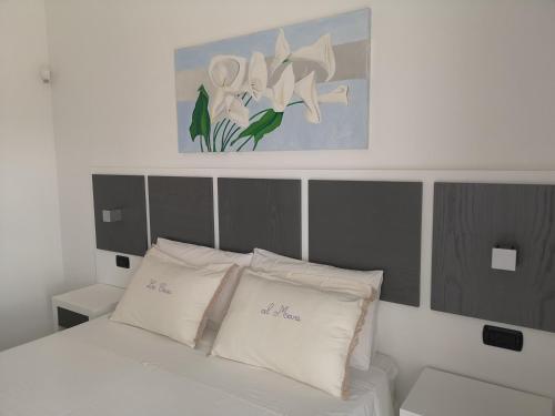 een bed met witte kussens en een schilderij erboven bij B&B Corallo in Capilungo