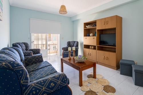 a living room with two blue chairs and a tv at Marinha- AL in Praia da Vagueira