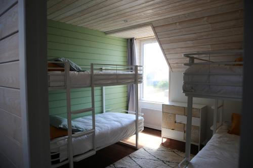2 Etagenbetten in einem Zimmer mit Fenster in der Unterkunft Ker Karreg (La Maison du Rocher) in Penmarcʼh