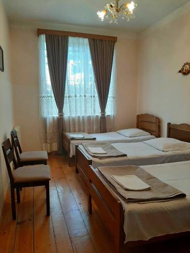 a bedroom with three beds and a chair and a window at Nitsa Guest House in Gori
