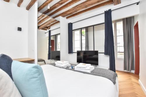 une chambre avec un lit blanc et une télévision dans l'établissement Authentic apartment 1BR-4P République - Le Marais, à Paris