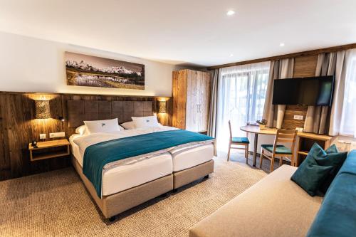 a hotel room with a large bed and a desk at Alpenhotel Wurzer in Filzmoos