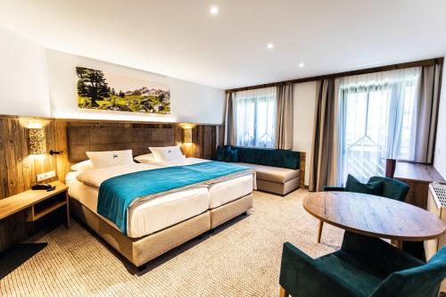 a hotel room with a bed and a table and chairs at Alpenhotel Wurzer in Filzmoos