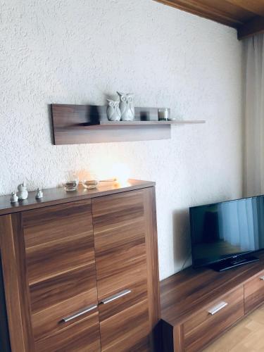 a living room with a tv and a wooden dresser at Ferienwohnungen Hecker in Bad Gögging