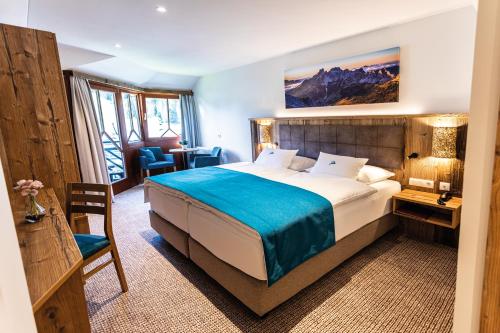 a hotel room with a large bed and a desk at Alpenhotel Wurzer in Filzmoos
