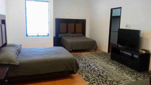 a bedroom with two beds and a flat screen tv at 10 Large suite for 4 people in Torreón