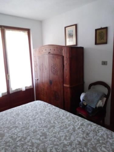 a bedroom with a bed and a chair and a window at Le Sapin 2 in Cogne