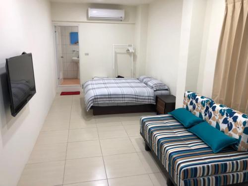 una stanza con due letti, una tv e un divano di La Pace Hostel a Città di Taitung