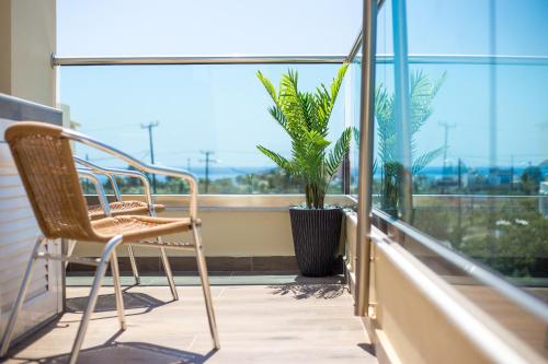 a balcony with two chairs and a potted plant at Billy's Studios in Faliraki