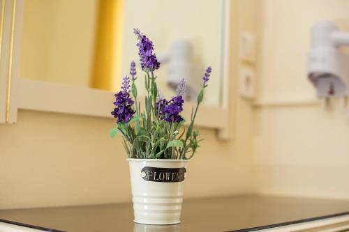 a white vase with purple flowers on a counter at Billy's Studios in Faliraki