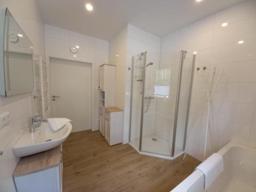 a white bathroom with a shower and a sink at Ferienhaus Piel - Am Inselwald in Ueckeritz