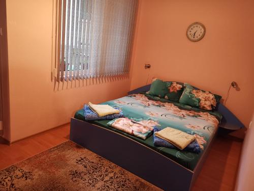 a bedroom with a bed with pillows and a clock at Нашето място in Pomorie