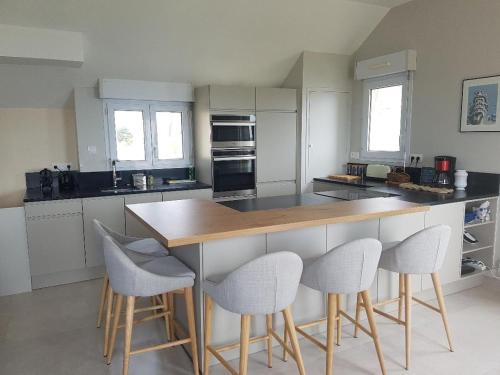 a kitchen with a island with four chairs around it at Le Cézembre - vue 180 baie St Malo in Saint Malo