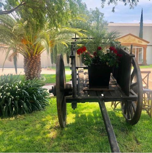 a cart with flowers in it sitting in the grass at Hotel la finca in Ezequiel Montes