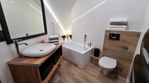 uma casa de banho com uma banheira, um lavatório e um WC. em Lux Apartment Loft em Polanica-Zdrój