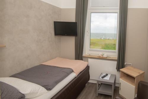 um pequeno quarto com uma cama e uma janela em Haus Neunaber em Norderney