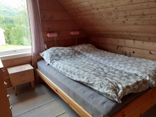 Haukedalen Feriehus في Viksdalen: سرير في غرفة خشبية مع نافذة