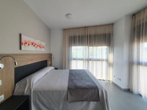 a bedroom with a bed and a large window at Iberflat Vega de Triana in Camas