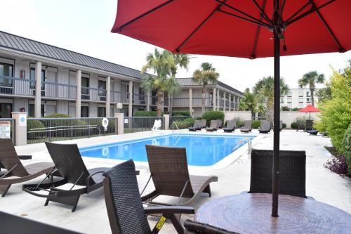 a table with an umbrella and chairs next to a pool at Ramada by Wyndham Savannah Gateway in Savannah